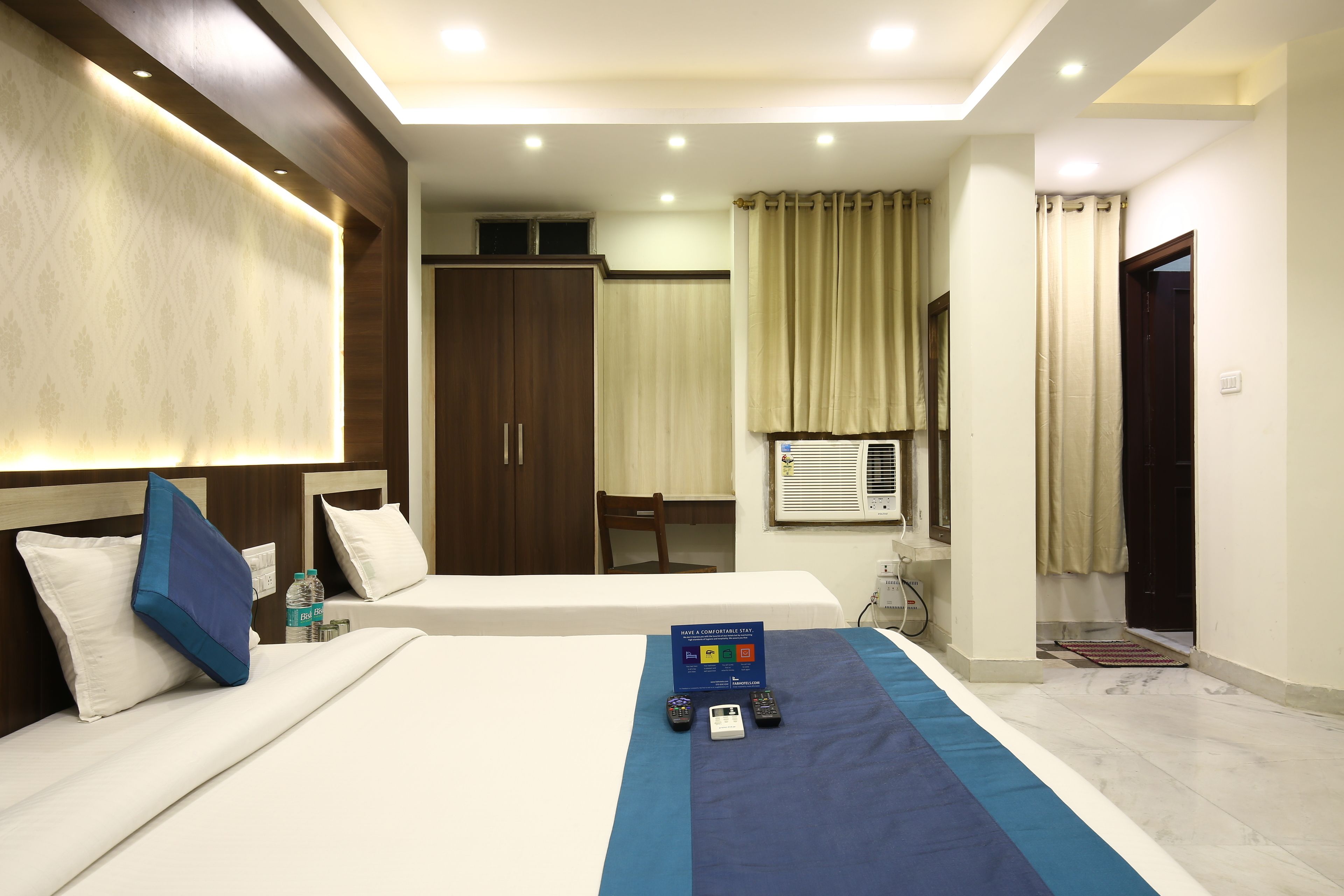 Habitación de hotel con dos camas, un minibar, un escritorio y una ventana con cortinas.