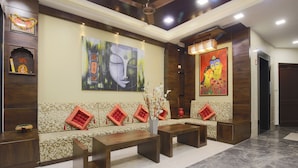 A lobby with a sofa set, a coffee table, and a vase with flowers. - Hotel Sagun (Jaipur)