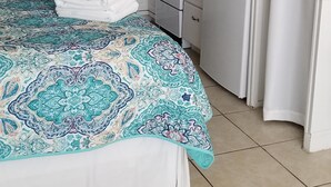 A bedroom with a bed, a ceiling fan, a kitchen with a refrigerator, and a bathroom with a curtain. - Popular   ~ Quaint. Bogue Shores Condo --  just steps to a beautiful beach (Atlantic Beach)