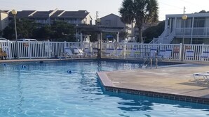 A swimming pool with a metal ladder leading into the water, surrounded by a white fence and lounge chairs. - Popular   ~ Quaint. Bogue Shores Condo --  just steps to a beautiful beach (Atlantic Beach)