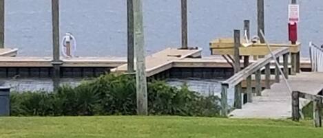 Propiedad frente al agua con muelle, zonas verdes y un edificio al fondo.