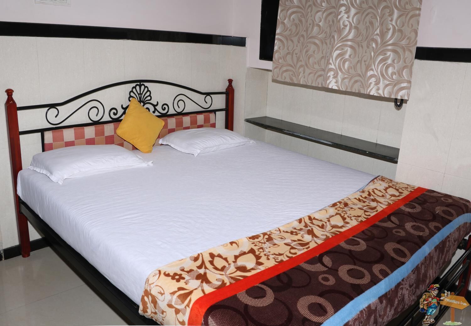 A neatly made bed with white linens and a decorative bedspread.