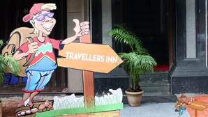 Cartell de Travellers Inn amb un personatge de dibuix animat fent el polze enaltit.