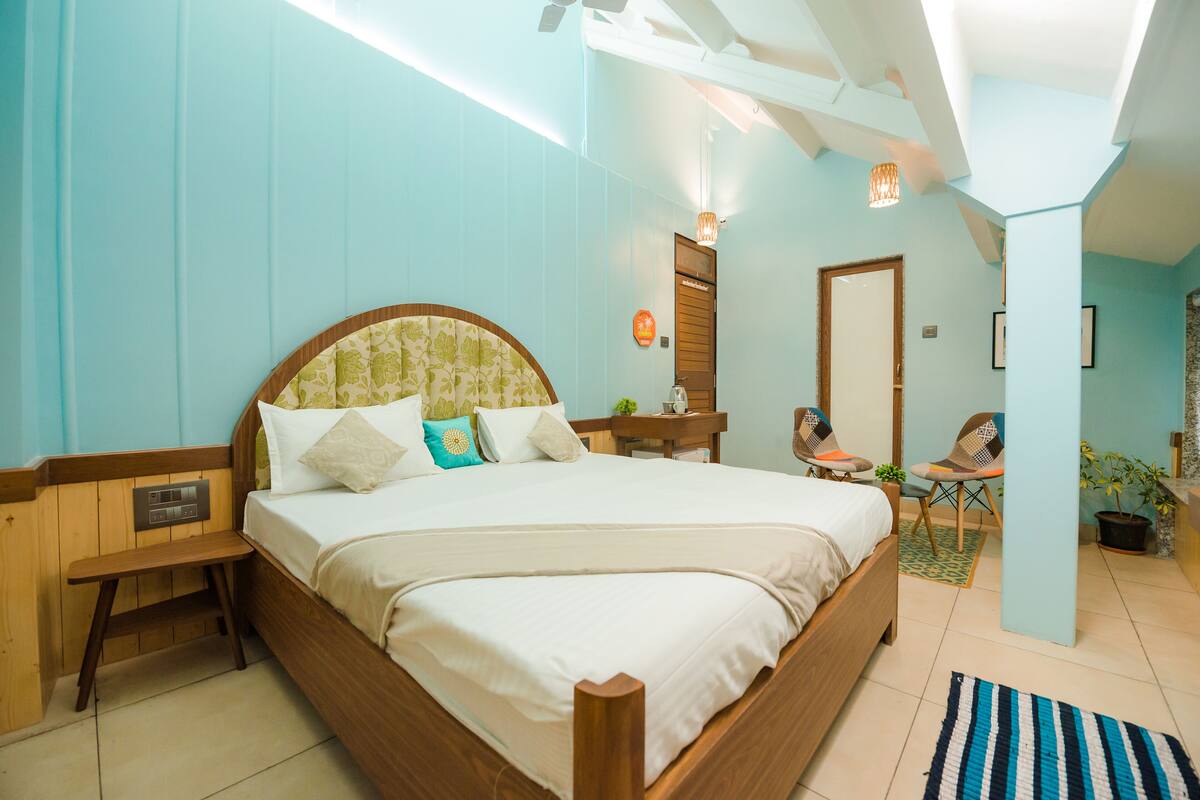 Une chambre à coucher avec un lit en bois, une table de chevet, une chaise et une petite table sur laquelle est posée une plante.
