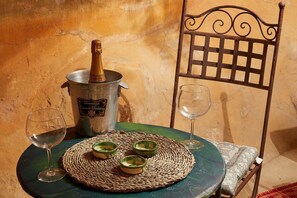 Una mesa con una botella de champán, tres copas y un mantel tejido.