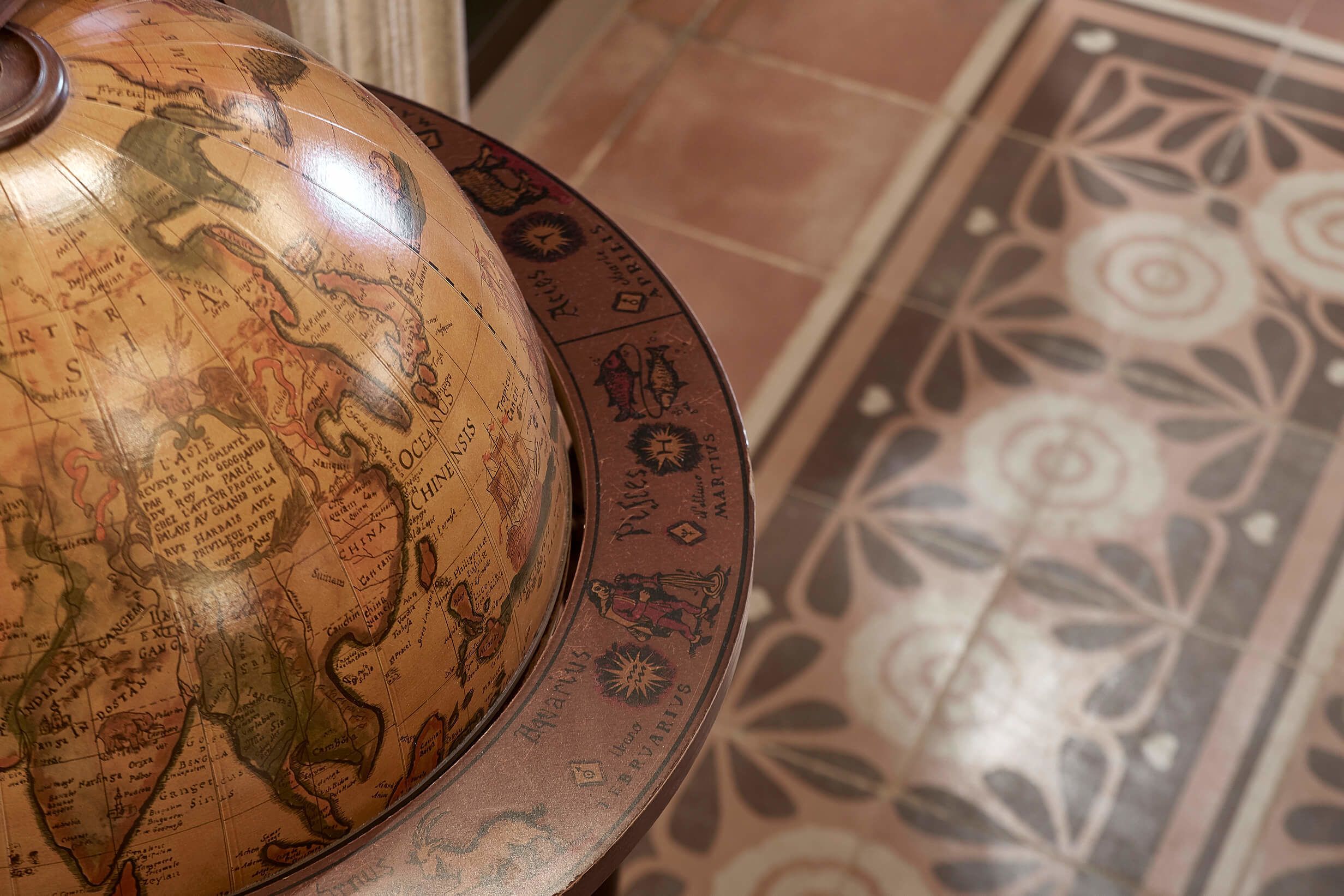 A globe with a detailed map, a patterned floor, and a decorative plate.