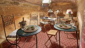 A rustic dining area with brick walls, metal chairs, and a table set with wine glasses and a candle holder. - Hotel Boutique La Indiana de Begur - Adults Only (Begur)