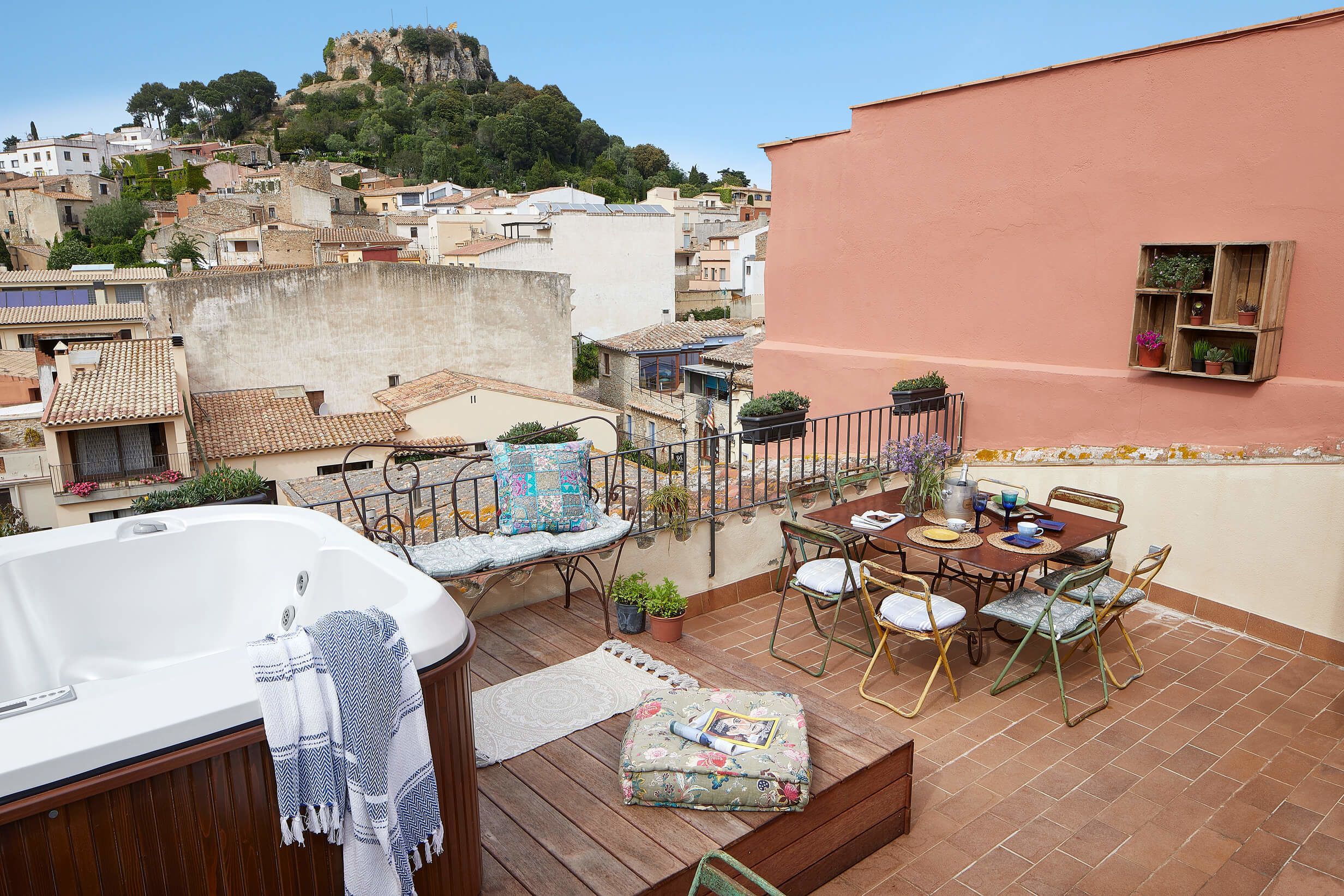 Terraza en la azotea con jacuzzi, mesa de comedor, sillas y plantas en macetas.