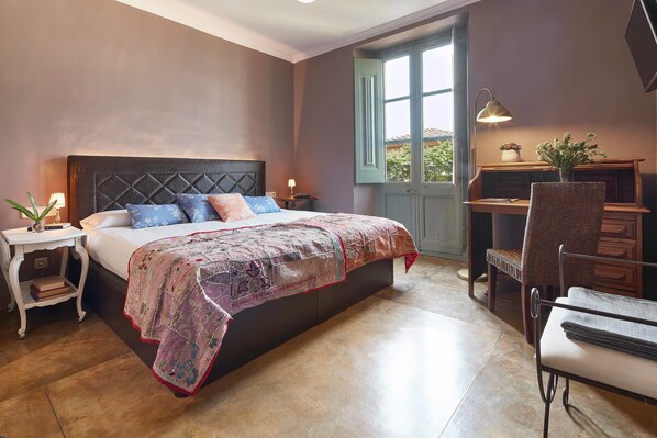 Un dormitorio con cama, mesita de noche, lámpara y escritorio con silla.