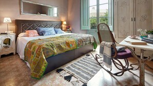 A bedroom with a large bed, a rocking chair, a desk, and a wardrobe. - Hotel Boutique La Indiana de Begur - Adults Only (Begur)