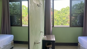 A room with two beds, a small table with a roll of toilet paper, and a door with a metal handle. - Bella Bella House (Bangkok)