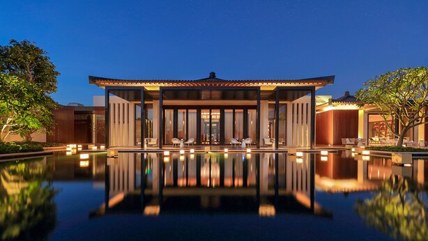 A modern building with a pool in front, surrounded by trees and a clear night sky. - Capella Tufu Bay, Hainan (Lingshui)