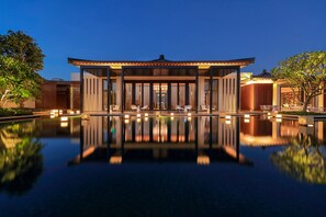 A modern building with a pool in front, surrounded by trees and a clear night sky. - Capella Tufu Bay, Hainan (Lingshui)