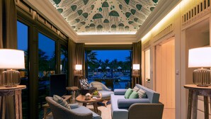 A well-lit lounge area with a ceiling design, comfortable seating, and a view of the pool area. - Capella Tufu Bay, Hainan (Lingshui)