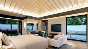 A modern hotel room with a large bed, a seating area, a TV, and a balcony with a view of the outdoors. - Capella Tufu Bay, Hainan (Lingshui)