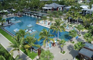 An aerial view of a resort with multiple swimming pools surrounded by palm trees and lounge areas. - Capella Tufu Bay, Hainan (Lingshui)