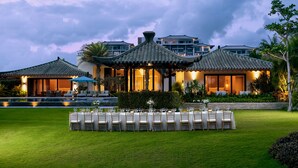 A traditional-style building with a well-maintained lawn and a dining area set up for an event. - Capella Tufu Bay, Hainan (Lingshui)