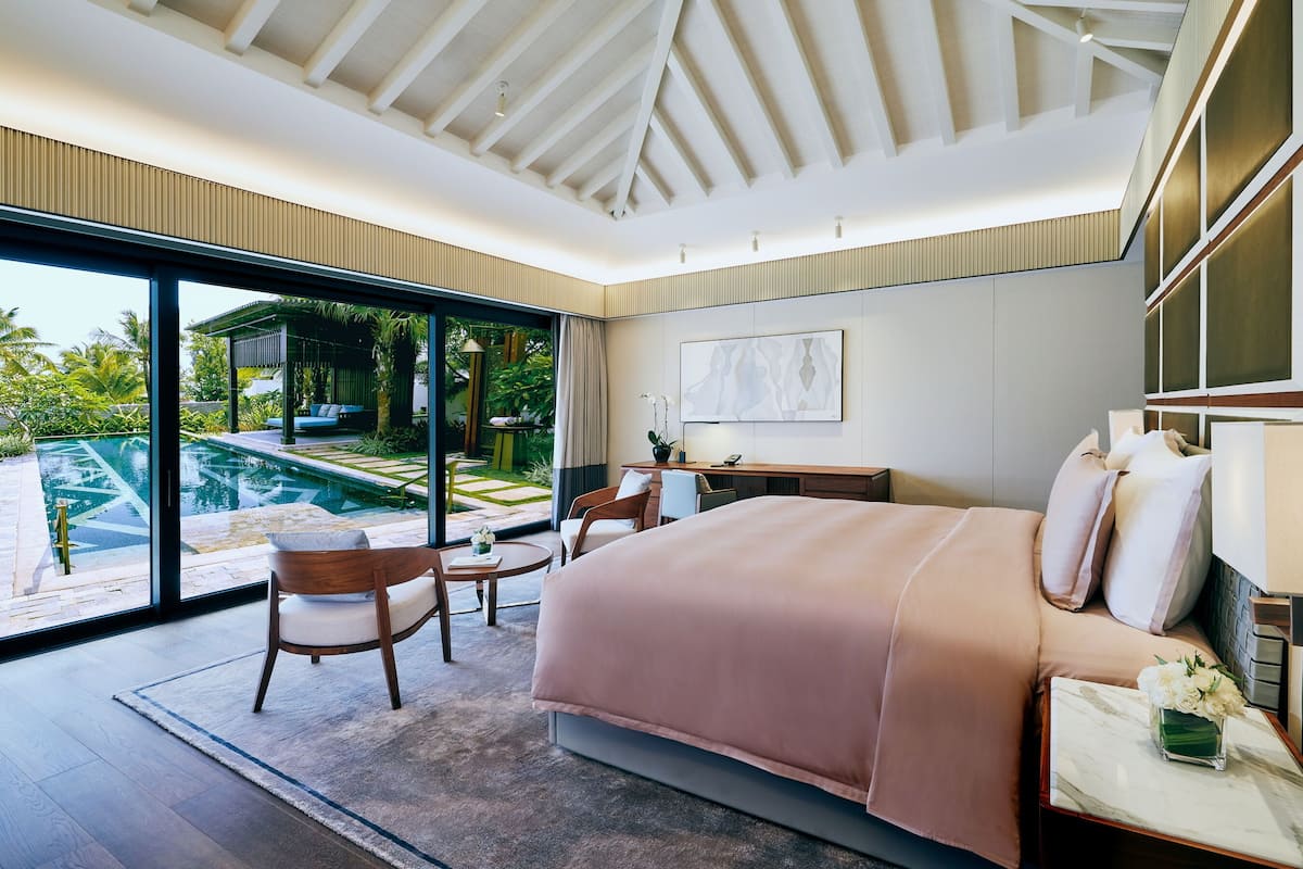 Une chambre moderne avec un grand lit, un bureau et une vue sur une piscine.