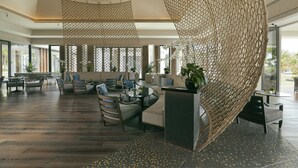 A spacious lobby with a modern design, featuring a seating area with sofas and chairs, a reception desk, and large windows providing natural light. - Capella Tufu Bay, Hainan (Lingshui)