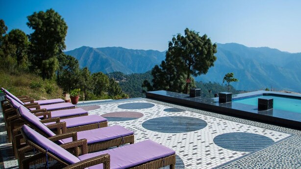 Área de piscina en la azotea con sillones de descanso y vistas a montañas.