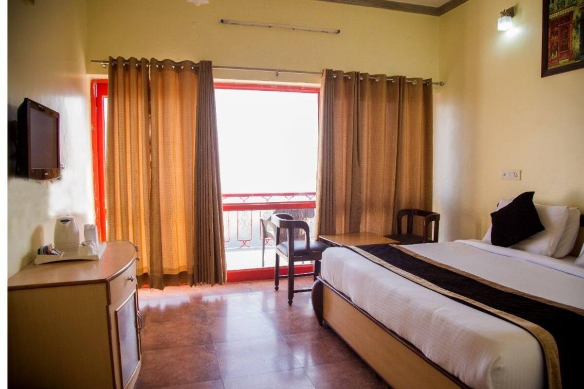 A hotel room with a bed, a desk, a chair, and a television.