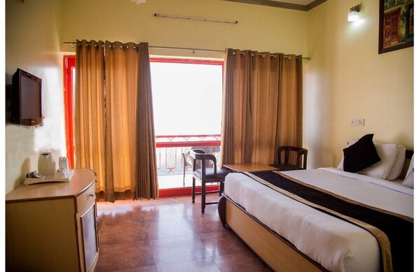 A hotel room with a bed, a desk, a chair, and a television.