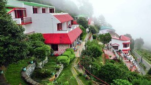 Un pueblo en la ladera con edificios tradicionales, un sendero pavimentado y abundante vegetación.
