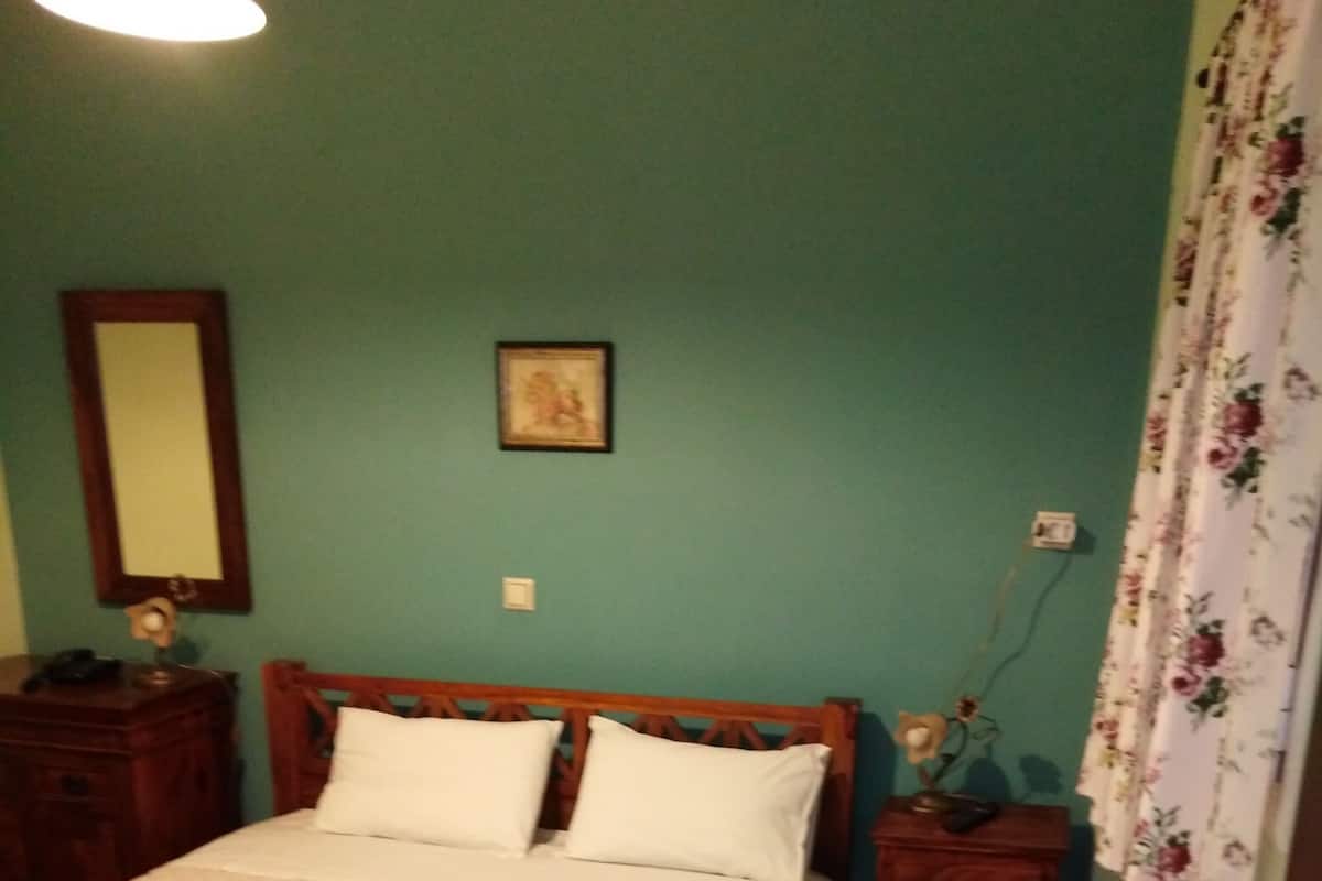 A neatly made bed with white linens and two folded towels on the bed.