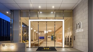 Das Außere des Monday Hotels mit einem modernen Eingang, Glasüren und einem einsehbaren Empfangsbereich.