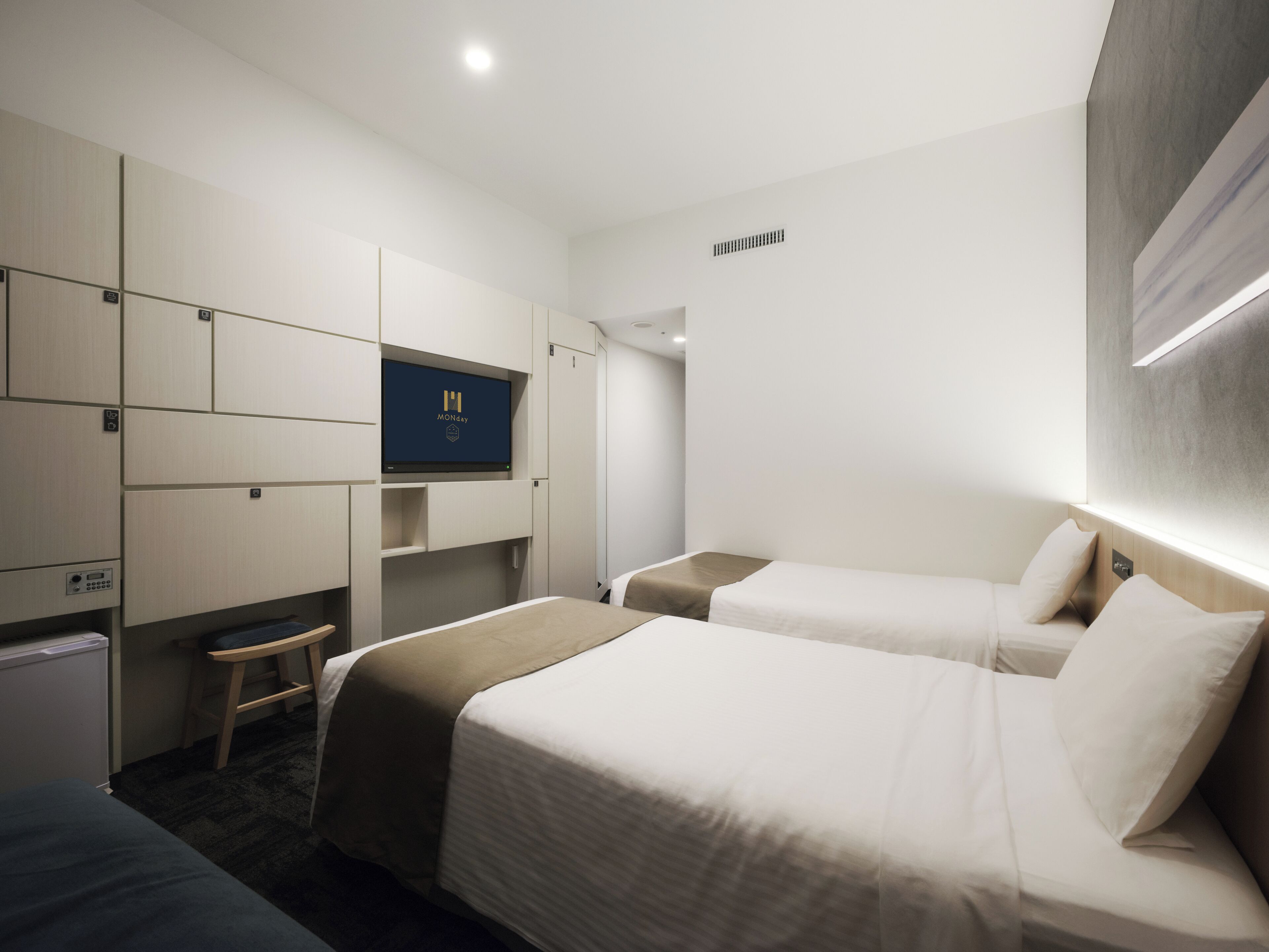 A hotel room with two beds, a desk, a TV, and a wardrobe.