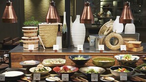 Ein Buffet mit verschiedenen Speisen und Schalen, begleitet von Kupferhängeleuchten und Korbwannen.