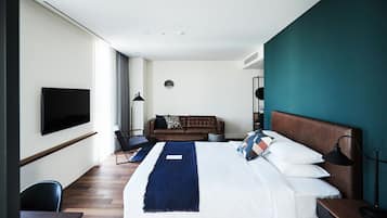 Una habitación de hotel moderna con una cama grande, un televisor de pantalla plana en la pared, un sofá y un escritorio con una silla.