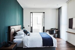 Una habitación de hotel moderna con cama, escritorio, silla y televisor.