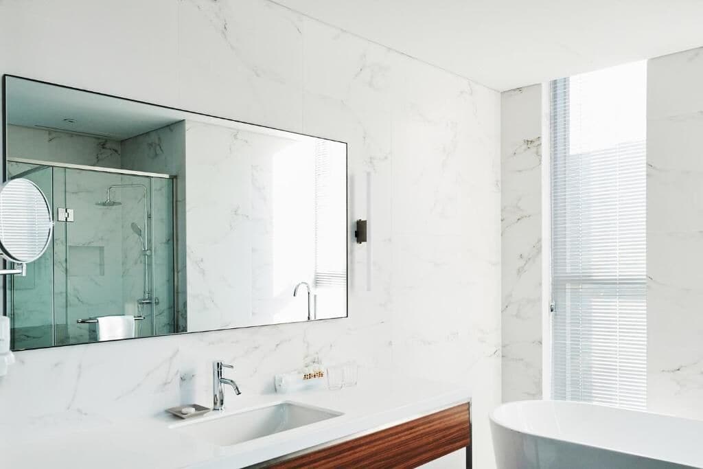 A modern bathroom with a marble sink, a large mirror, and a glass-enclosed shower.