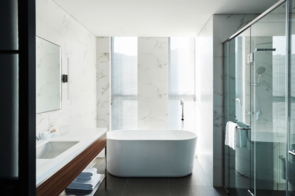 A modern bathroom with a freestanding bathtub, a glass shower enclosure, and a large mirror above the sink.