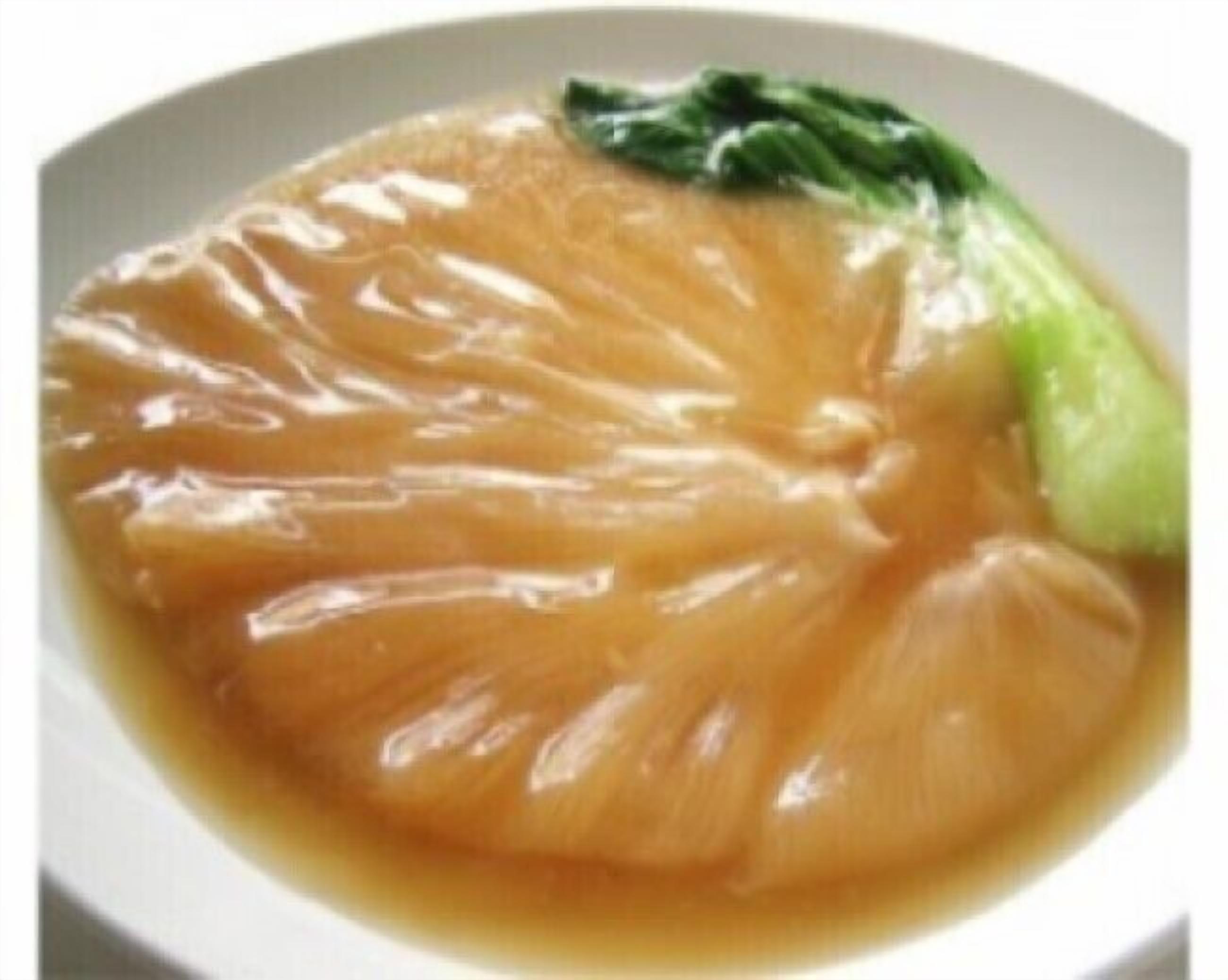 A bowl of clear broth with a piece of meat and a green vegetable.