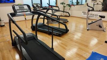 A gym with treadmills, a stationary bike, and a blue step platform.