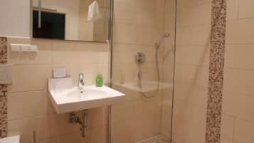 A modern bathroom with a glass-enclosed shower, a white sink, and a mirror above it.
