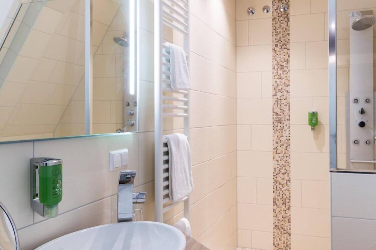Een moderne badkamer met een grote spiegel, een wastafel, een douche en een handdoekrek.