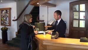 A reception desk with a wooden counter, a green chair, and a small bell. - Burg Warberg (Warberg)