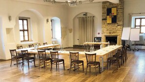A conference room with a long table, chairs, a fireplace, and a stone wall. - Burg Warberg (Warberg)
