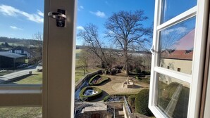 A view from a window overlooking a landscaped garden with a winding path, a circular flower bed, and a small pond. - Burg Warberg (Warberg)