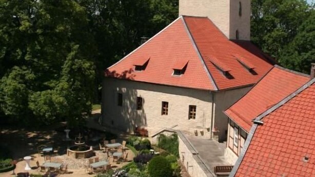 A historic building with a red-tiled roof, a tower, and a flag. - Burg Warberg (Warberg)