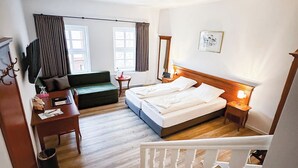 A bedroom with a bed, a desk, a chair, a sofa, a TV, and a window. - Burg Warberg (Warberg)