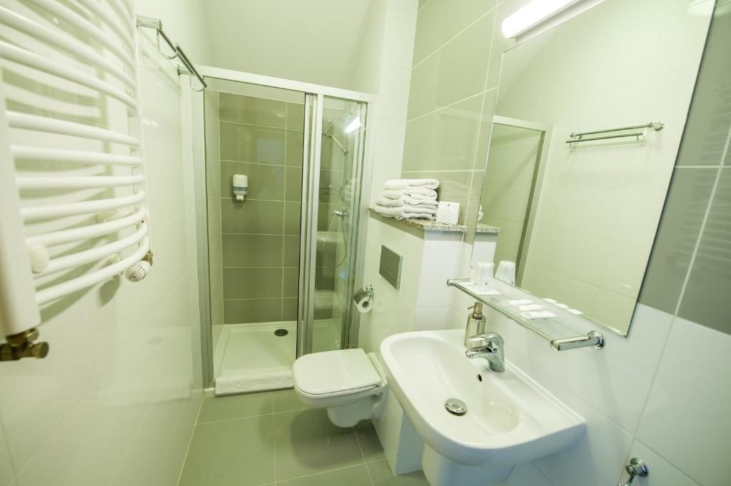 A modern bathroom with a glass shower enclosure, a white toilet, a bidet, and a sink with a mirror above it.