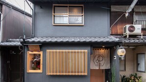 Een traditionele Japanse woning met pannendak, een houten raam en een kleine ingang met een schuifdeur.