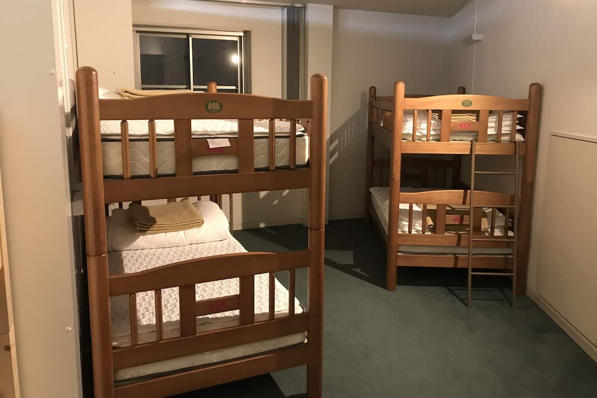 A room with two bunk beds, a window, and a radiator.