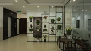 Een hotellobby met een receptiebalie, een zithoek en potplanten.
