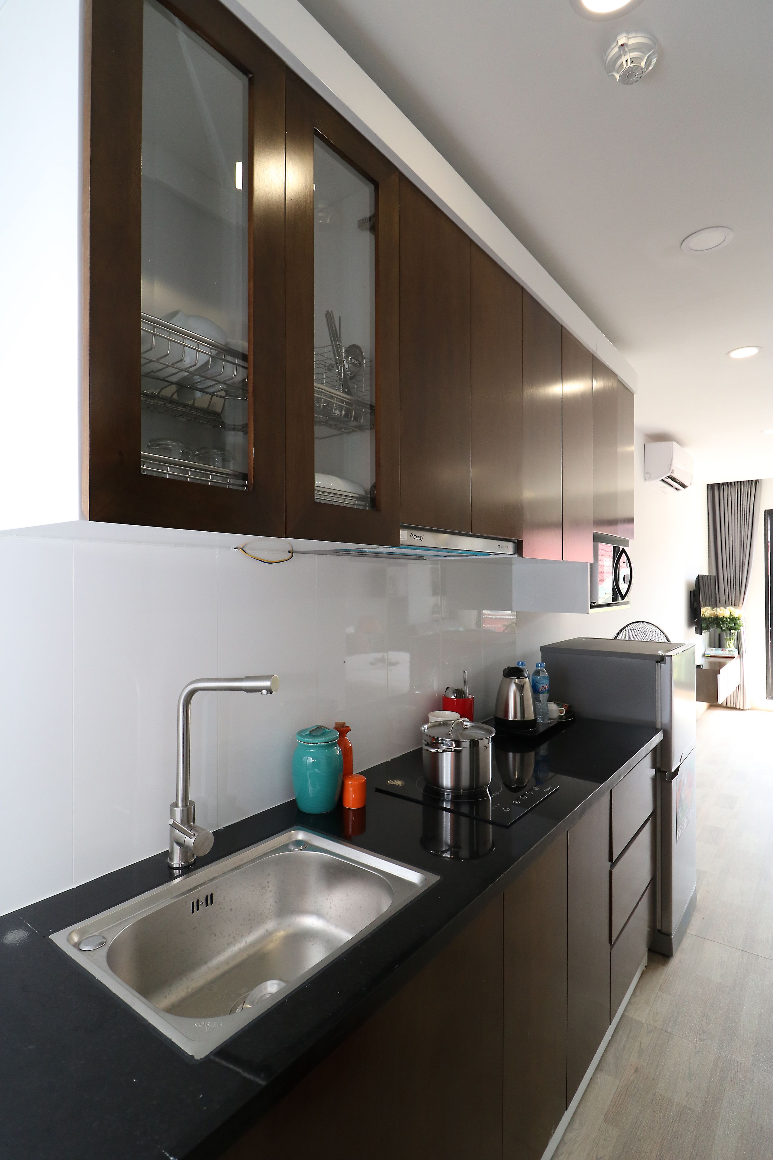 A modern kitchen with a stainless steel sink, dark wooden cabinets, and a black countertop.