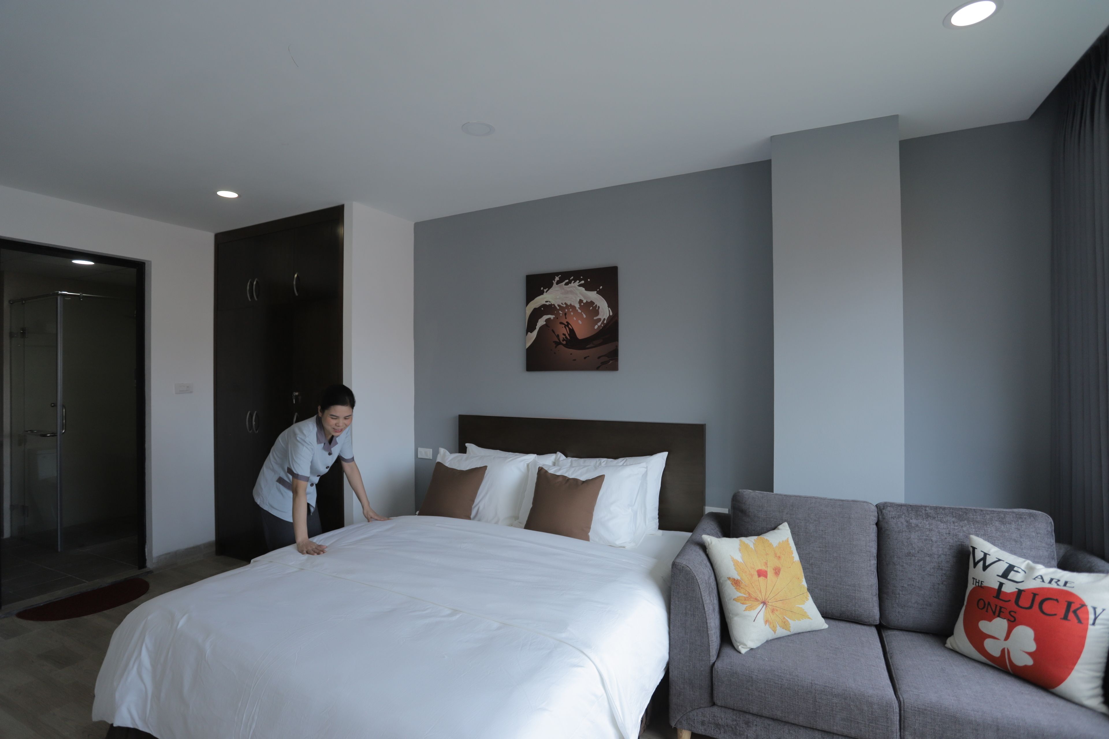 Una habitación de hotel con una cama grande, un sofá gris y un cuadro en la pared.